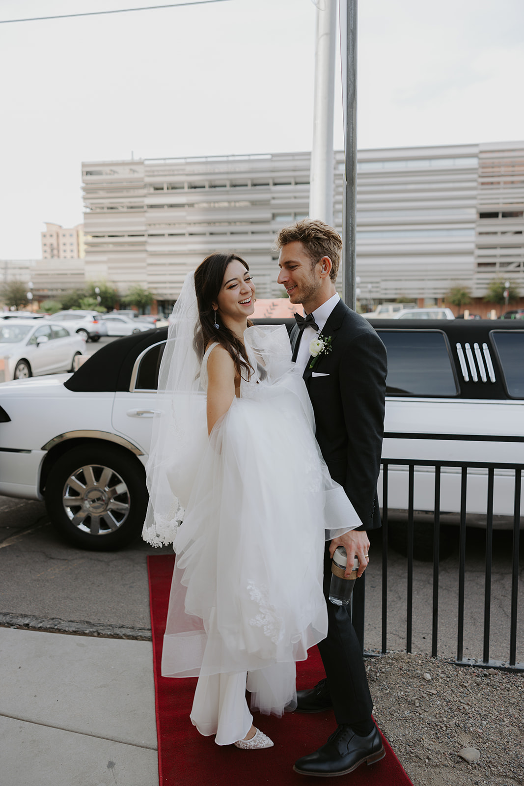 Bride and groom in front of classy limo at ASU All Saints Catholic Newman Center in Tempe Arizona
