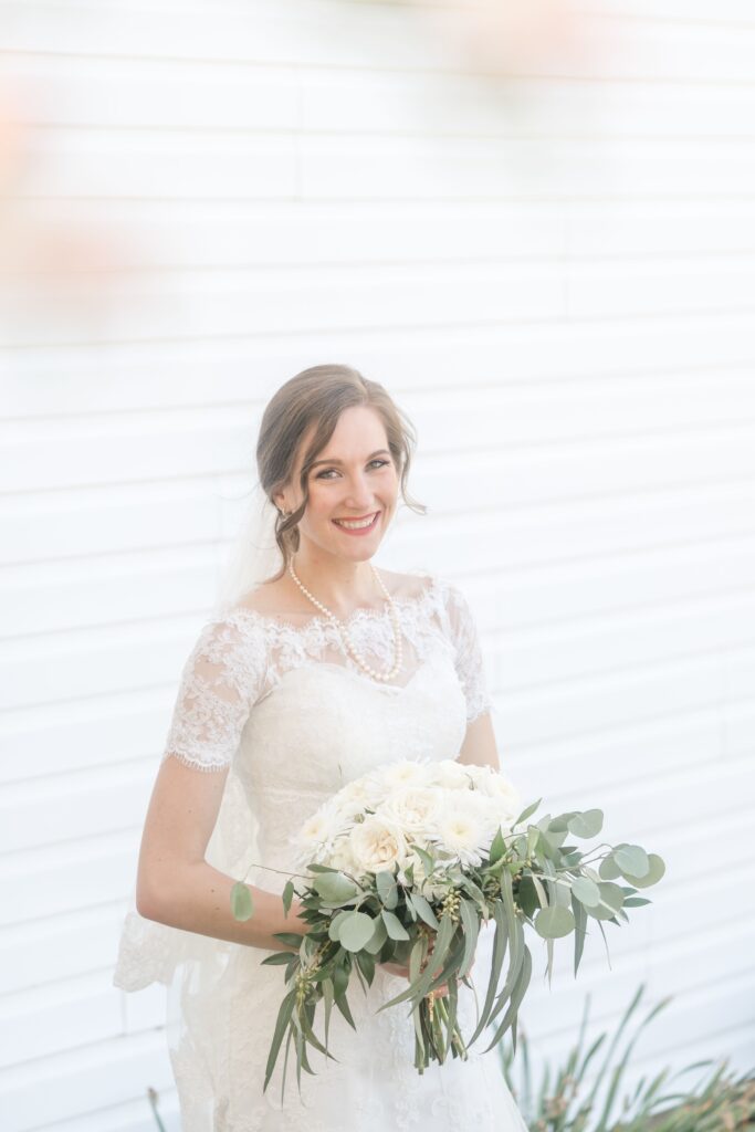 A bride holding a bouquet of white flowers made by Mystical Rose Flowers