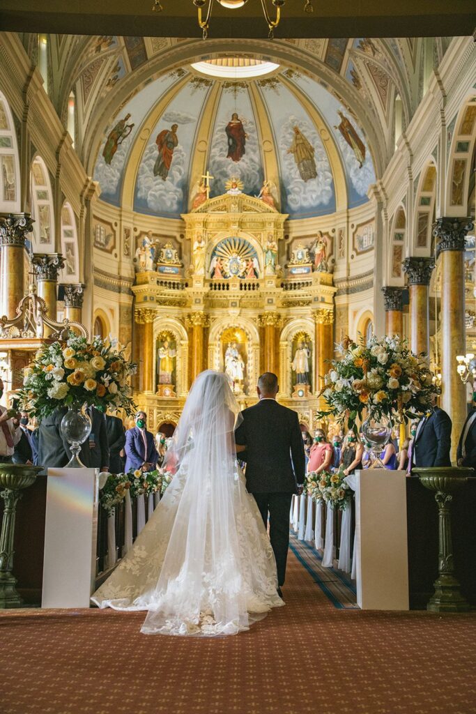 A bride and her father about to process down the aisle of a Catholic Church. 