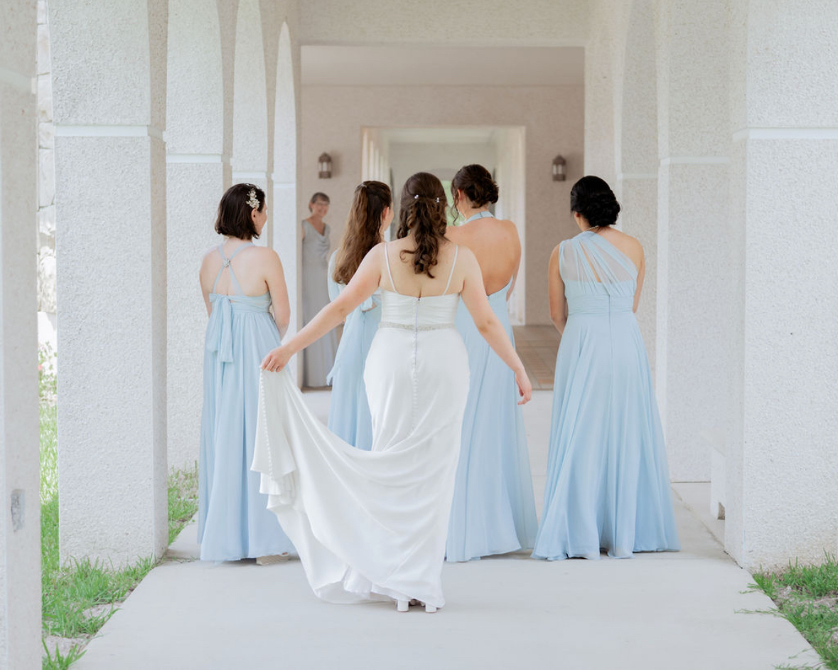 A group of bridesmaids waits with their backs turned to see the bride